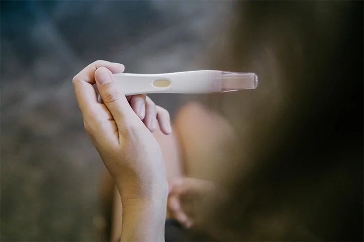 A woman dealing with female infertility issues holding a pregnancy test