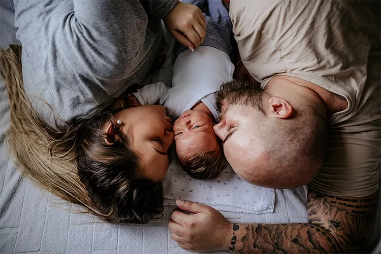 A couple laying in the bed with their child