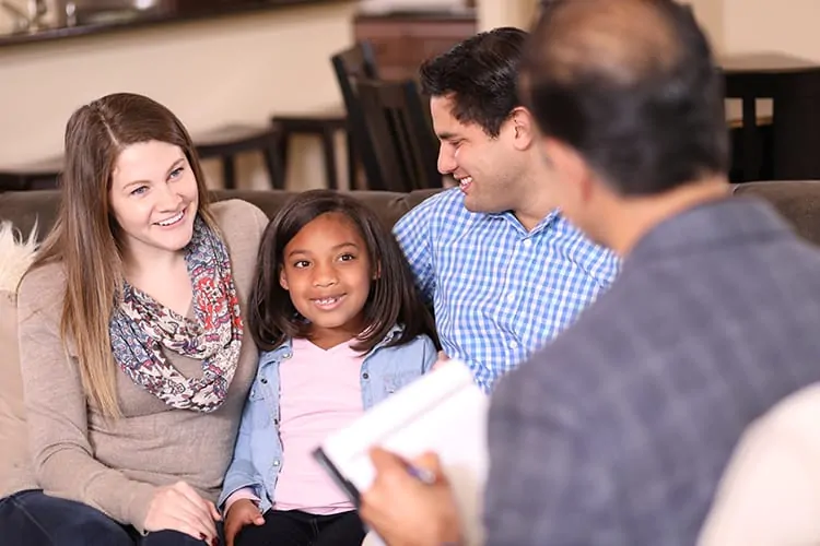 A couple with their adopted daughter talking to a representative from an adoption agency