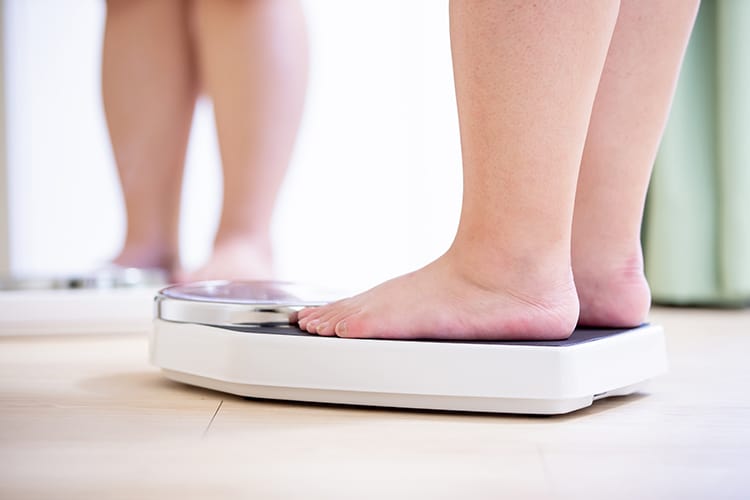 Woman on a weight - overweight may cause fibroids in the uterus